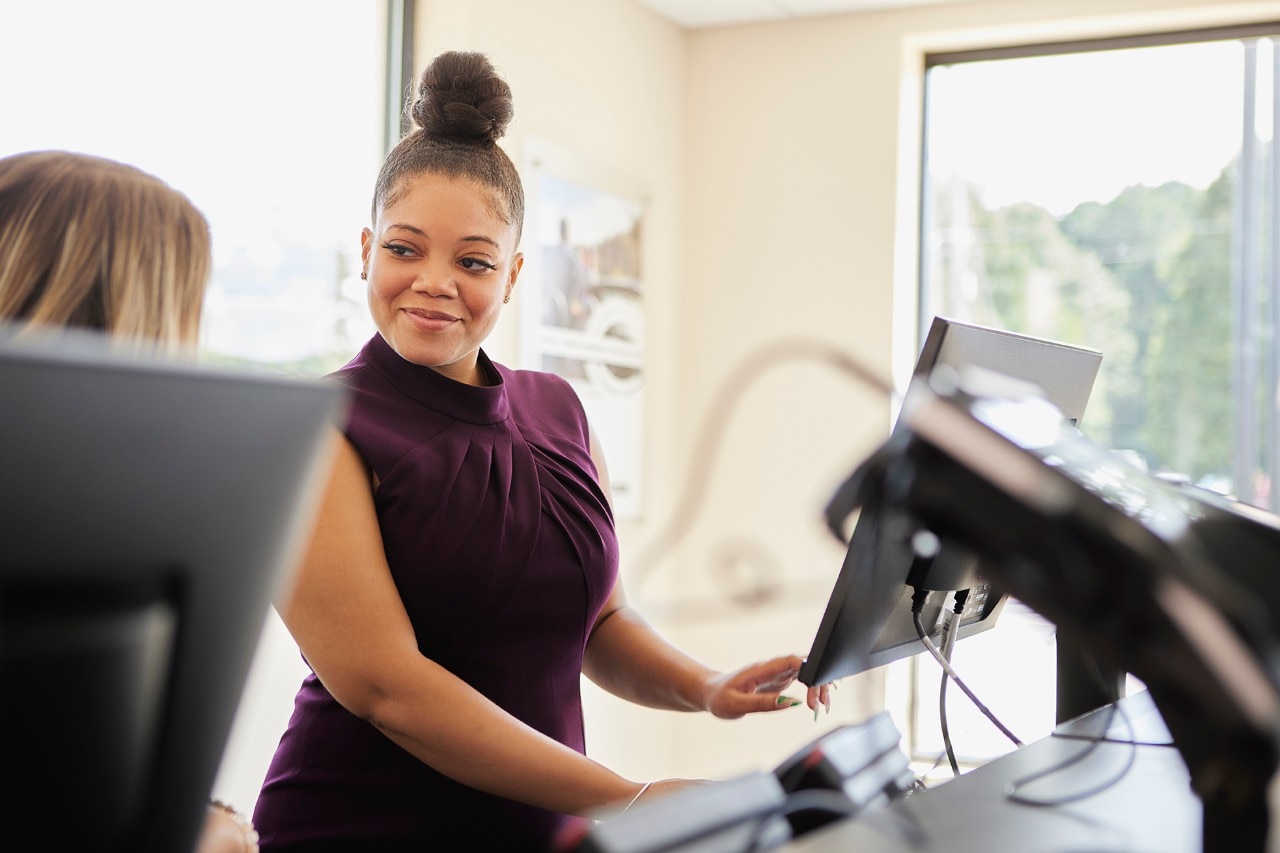 Enterprise Mobility team member speaking to another team member from behind the counter of a neighborhood branch retail office. 