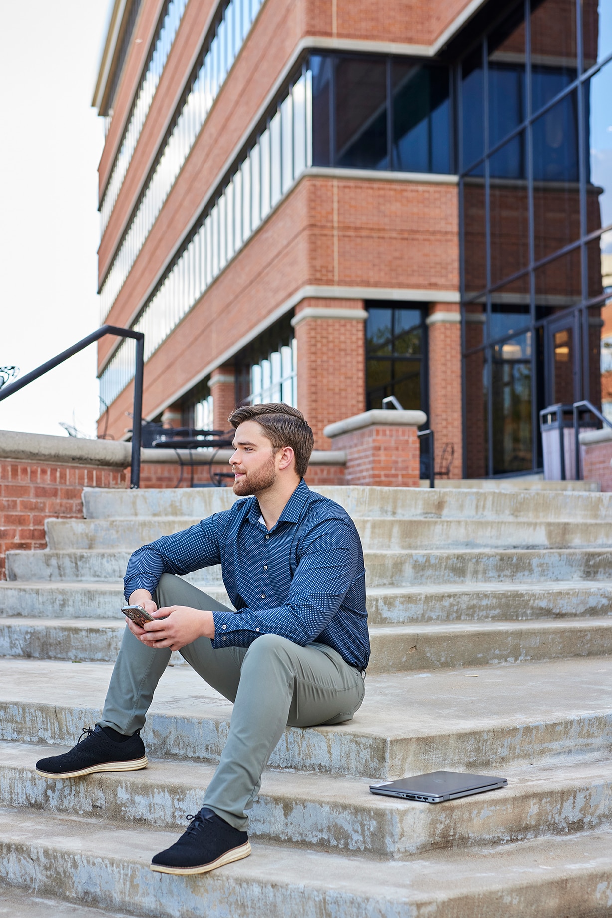 Enterprise Mobility team member sitting outside the outside the global head office in St Louis, MO with a laptop and phone. 