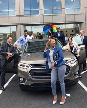 Group of employees in and around a rental car