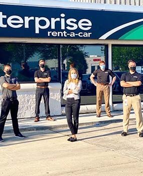 Employees wearing masks in front of Enterprise branch
