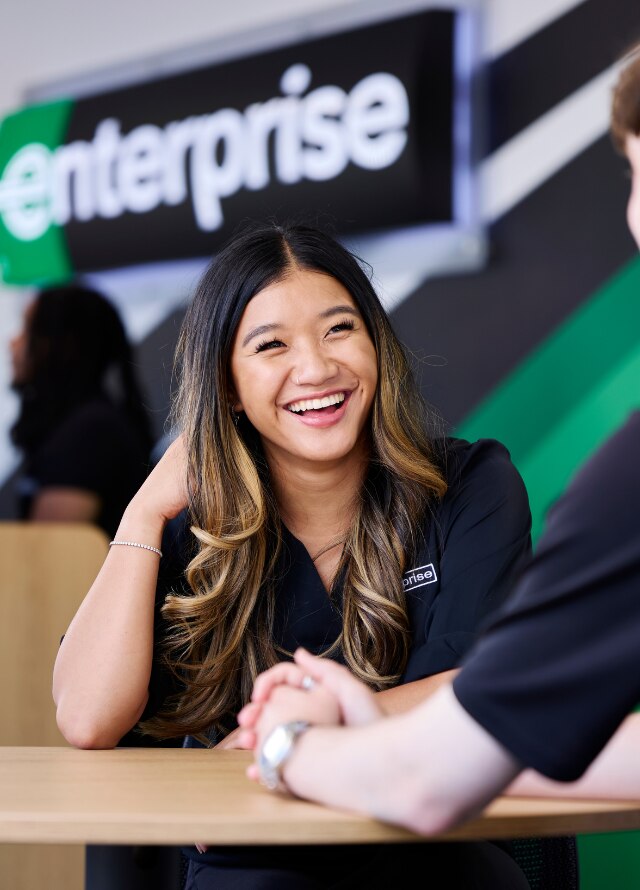 Enterprise Mobility team member speaking to another team member from behind the counter of a neighborhood branch retail office. 
