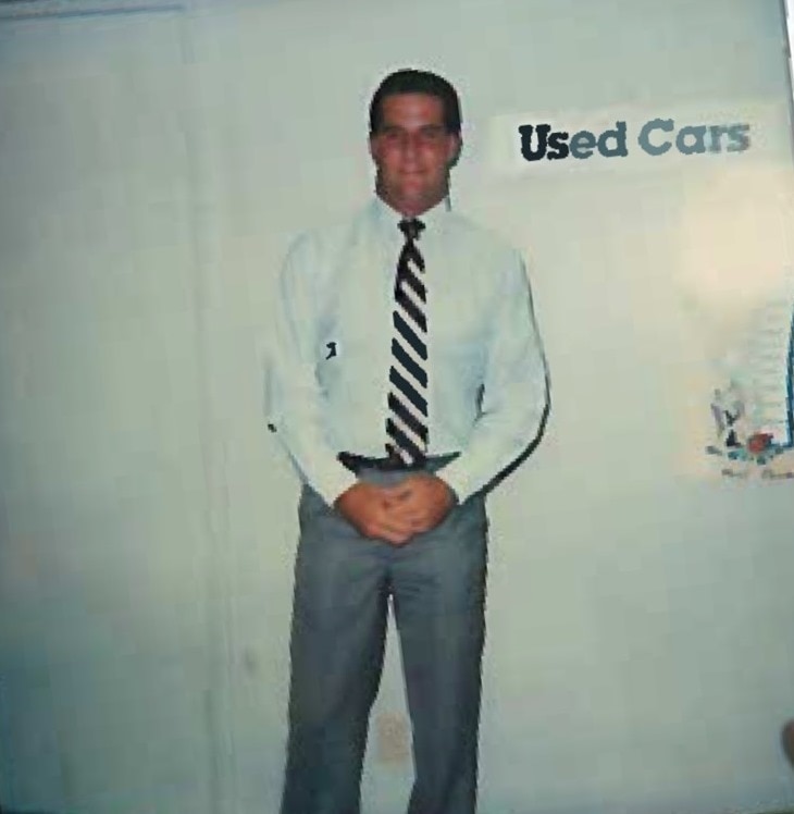 Howard in front of "Used Cars" sign