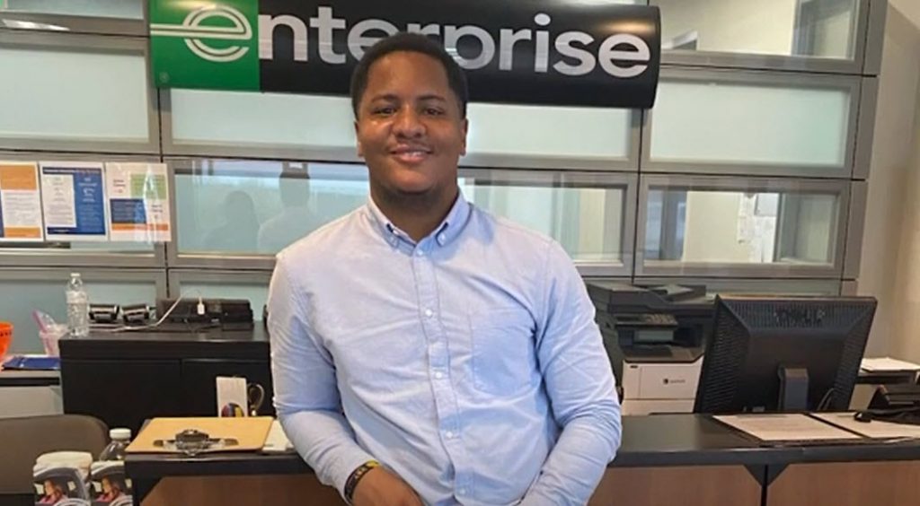 Tyquavious at his desk with Enterprise banner behind him