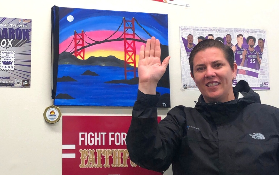 Tammy raising her right hand in front of art work