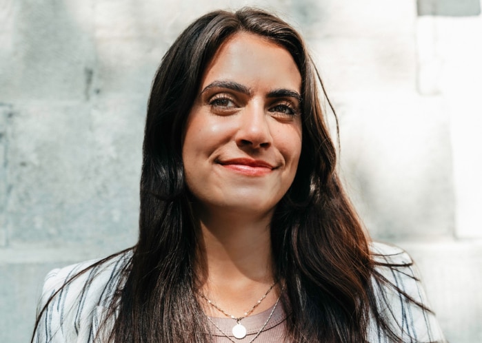 Woman standing against a grey wall.