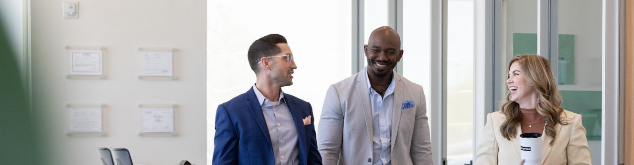Three Enterprise Mobility team members talking while walking in a neighborhood branch retail office. 